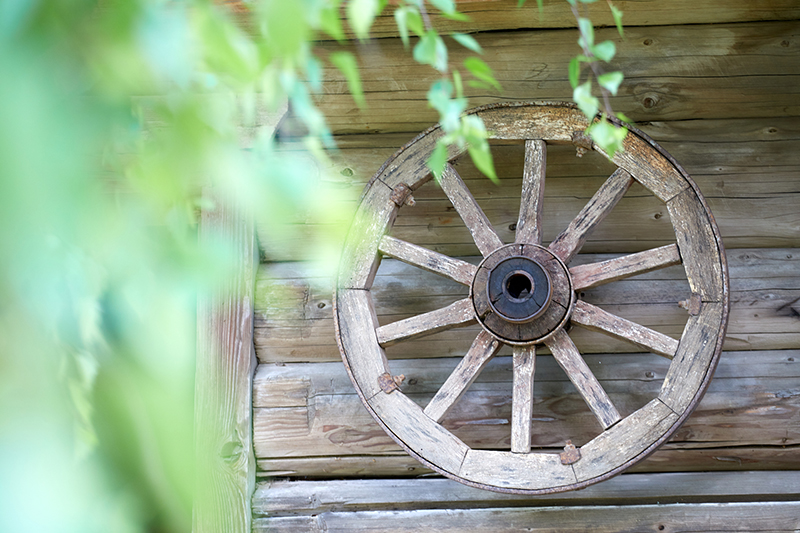 old wooden wheel next to a house