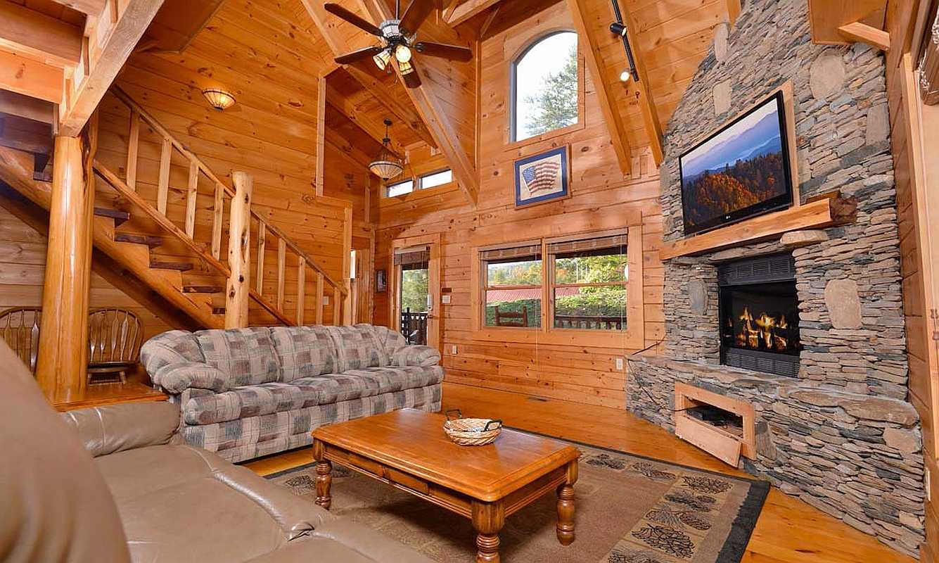 Interior view of the Madison log home's living room, showcasing a cozy fireplace, rustic wooden beams, and comfortable seating