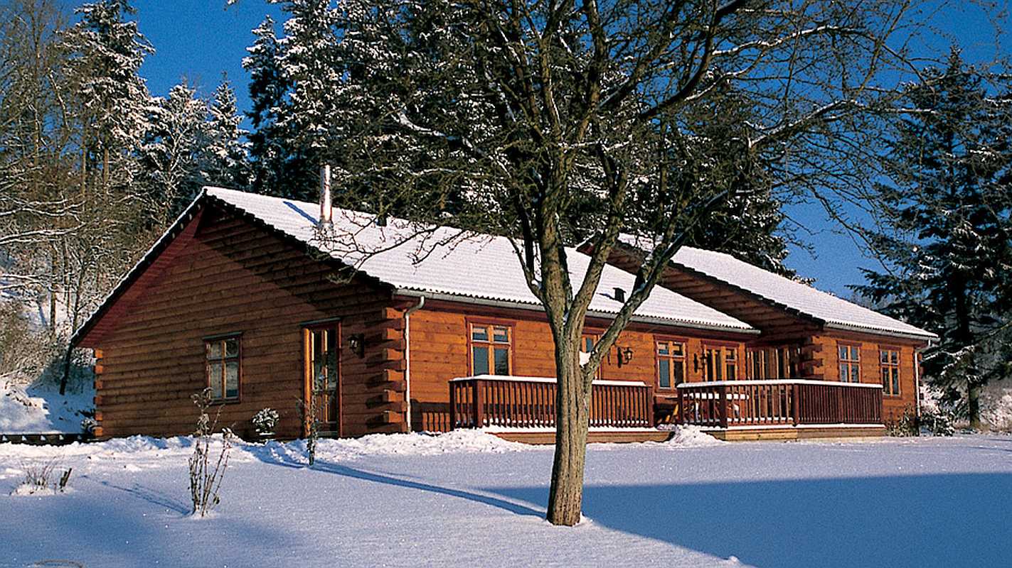 Snow Covered Log Cabin Surrounded by Snow and Trees