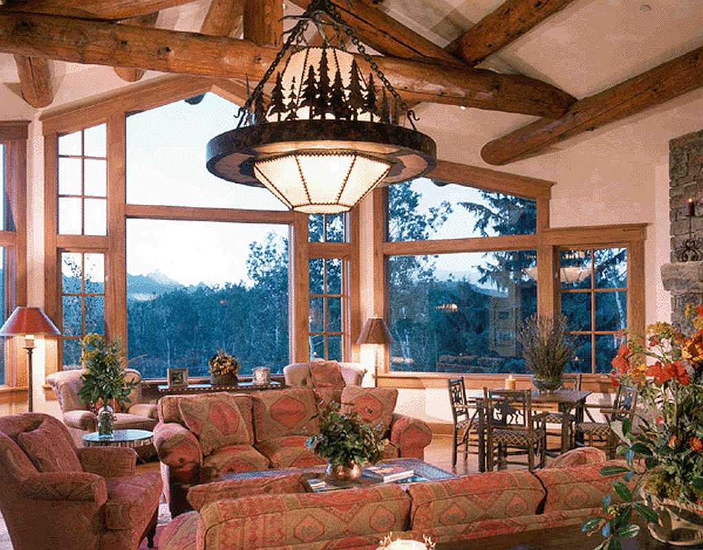 Interior Living Room of Log Cabin With Open Windows Facing Mountains and Greenery