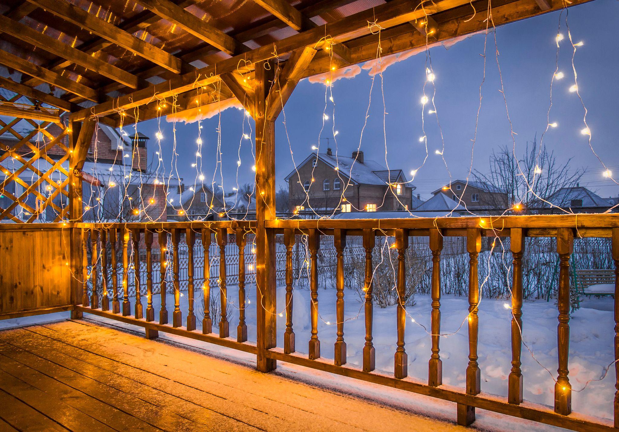 Cabin deck with string lighting on railing.